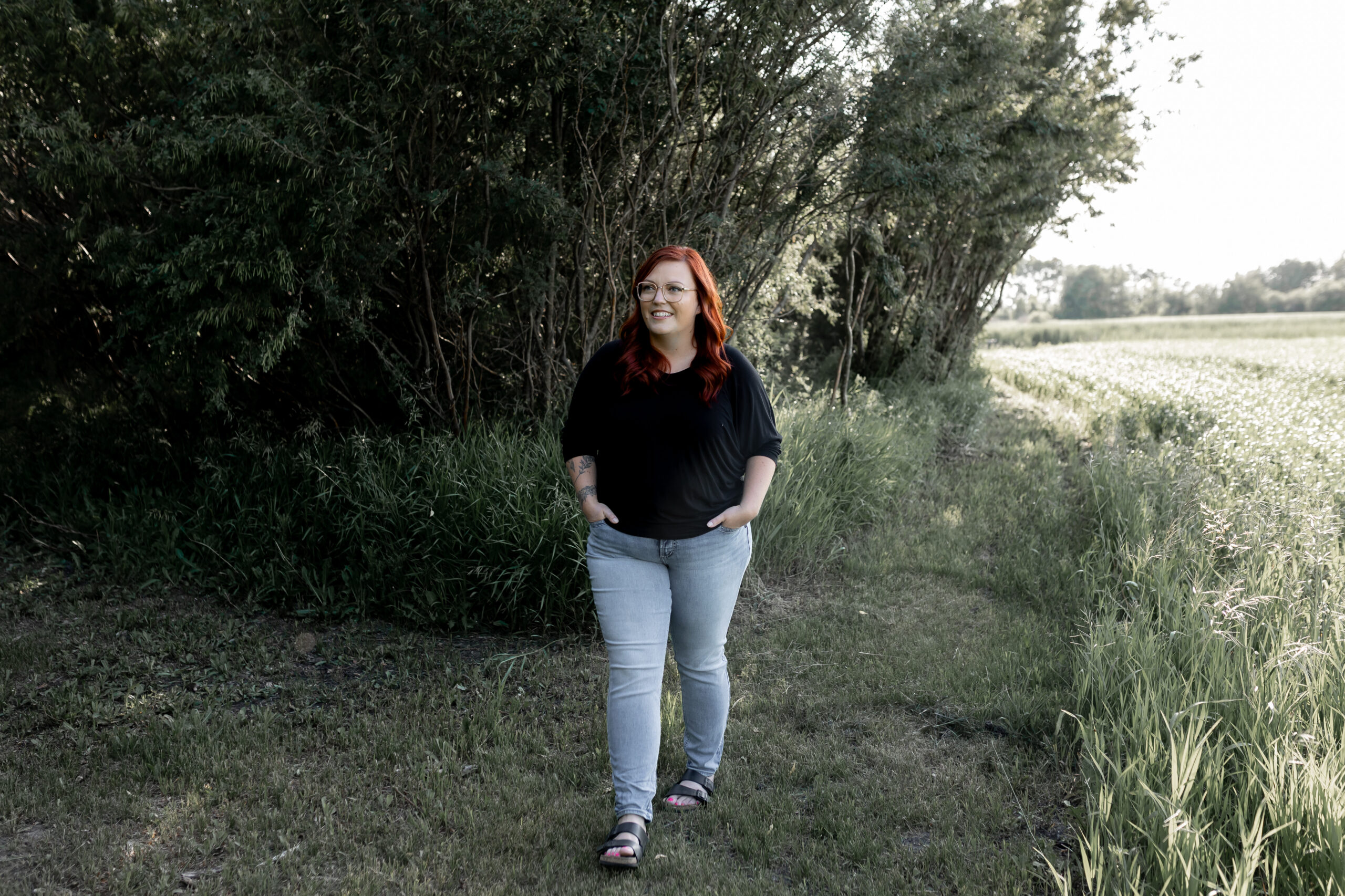 Red haired women walking through a grassy path beside a wheat field.