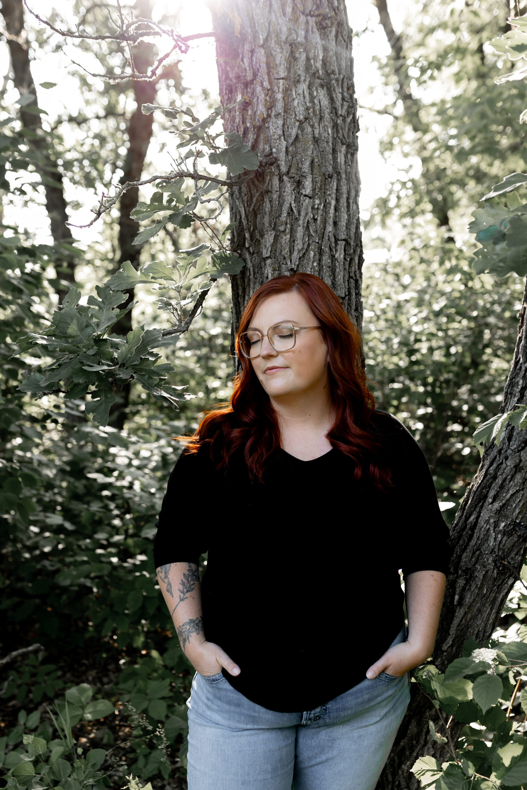 Red haired women leaning against an old oak tree